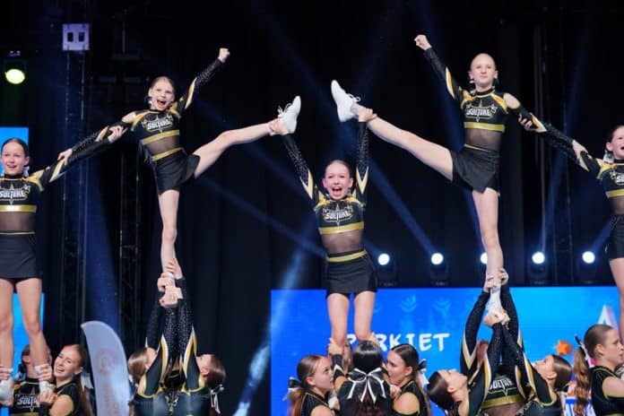 Grupa cheerleaderek z Olsztyna podczas występu na mistrzostwach Polski, wykonujących akrobatyczny układ.